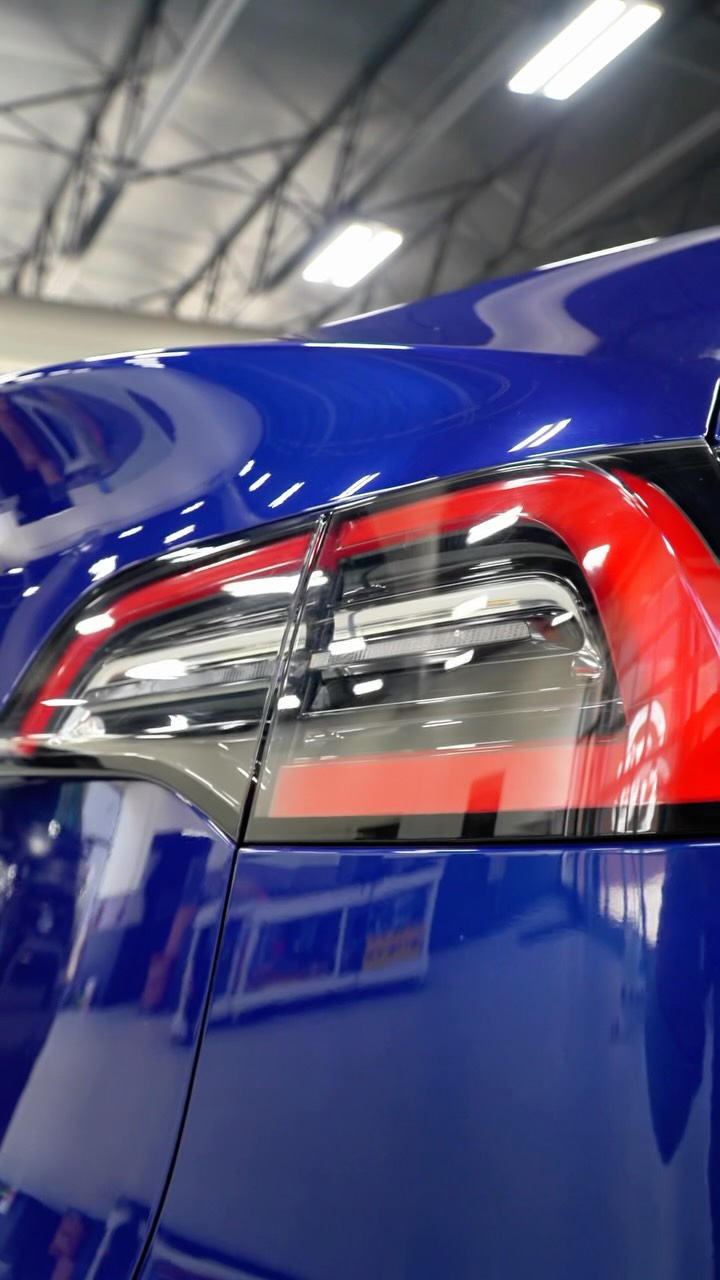 Rear taillight of a blue Tesla with paint protection film applied