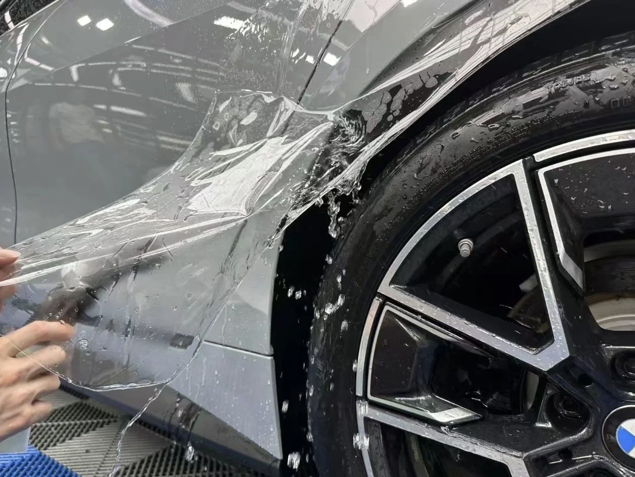 FILMHAUS installer applying paint protection film around a BMW wheel arch